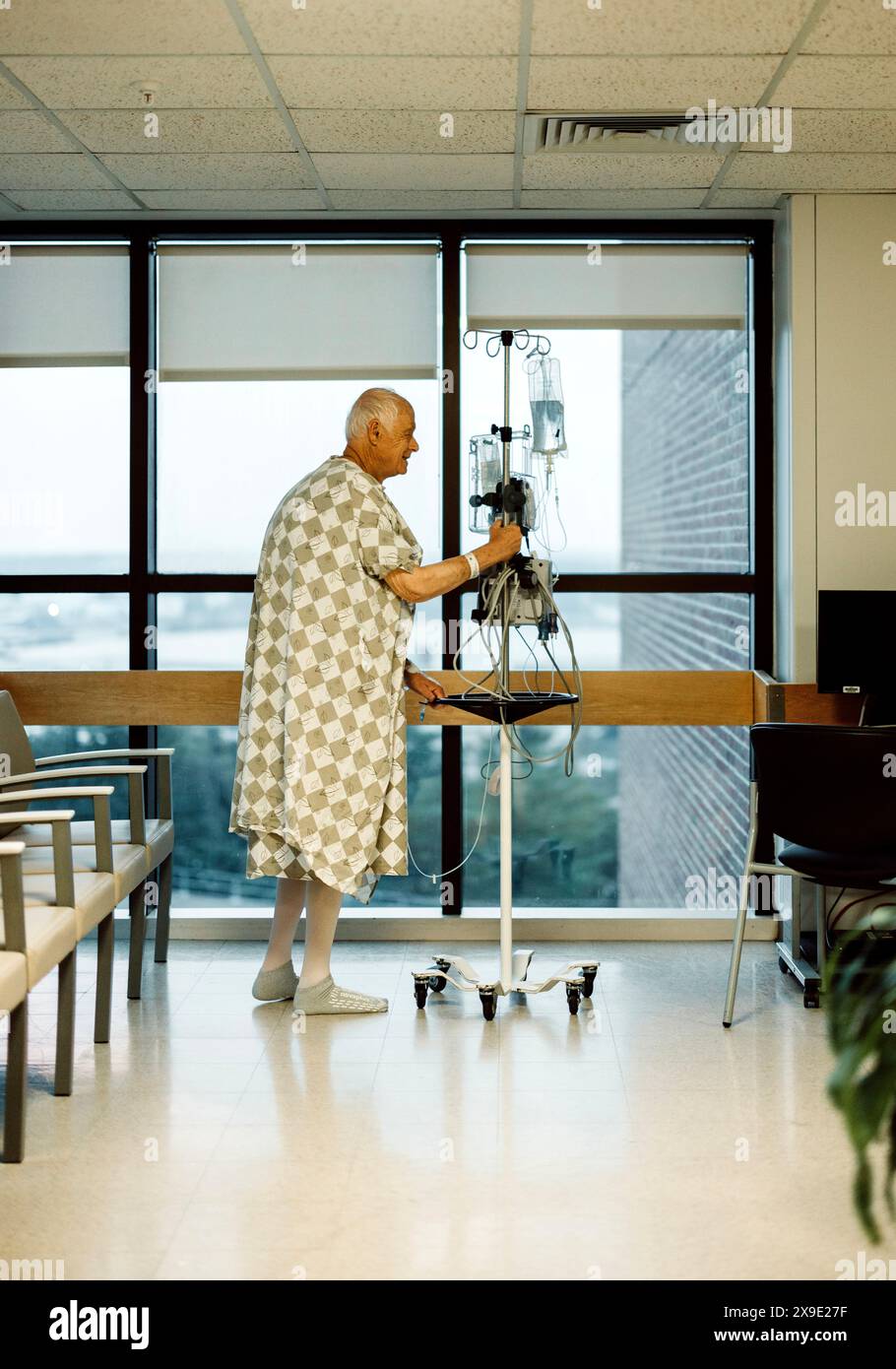 Älterer männlicher Krebspatient lächelt beim Spaziergang im Krankenhaus Stockfoto