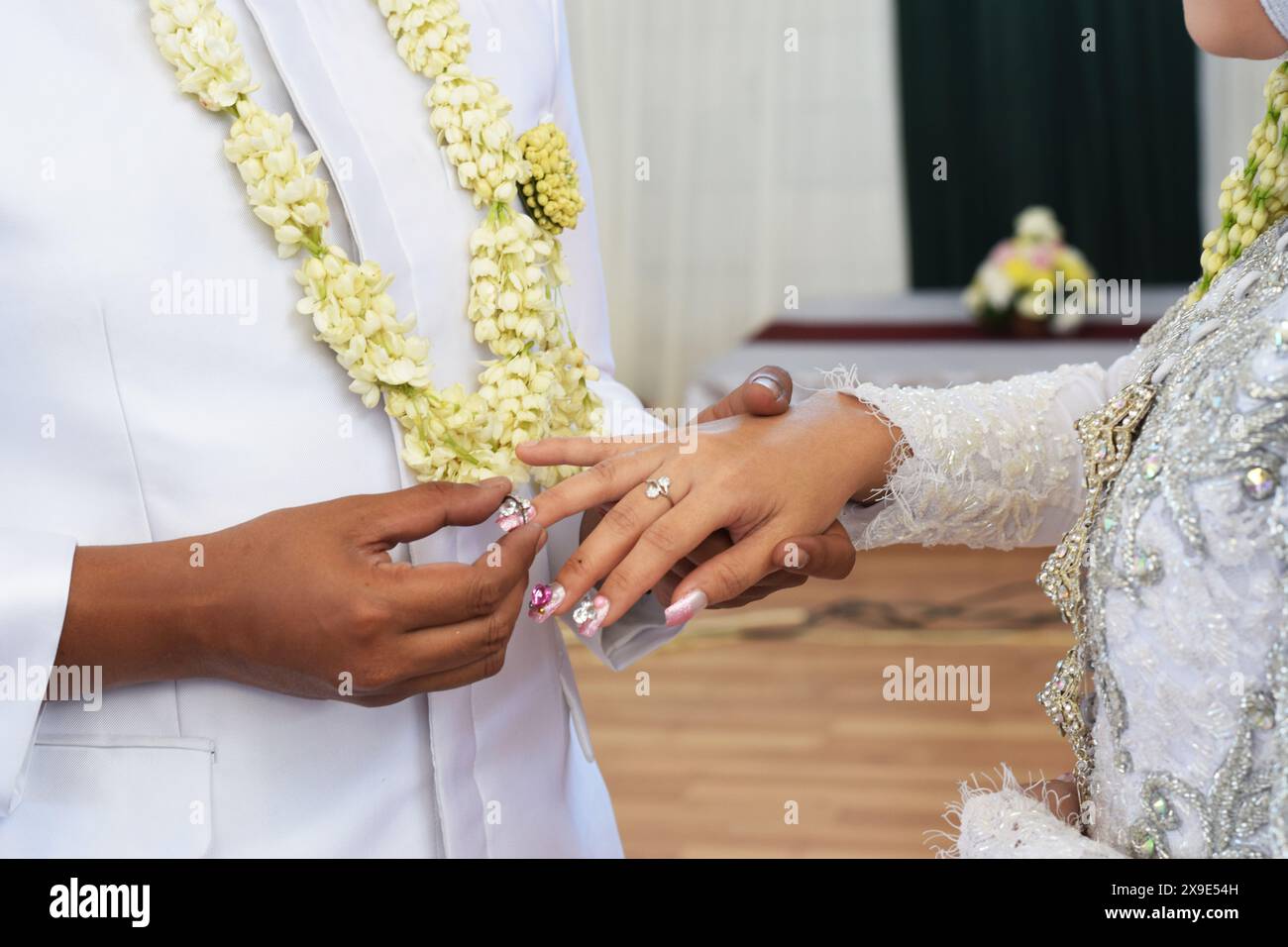 Die Braut, der Ehering und der Bräutigam halten die Hände. Zeigen die Wärme ihrer Beziehung, Liebe und Respekt zueinander. Stockfoto