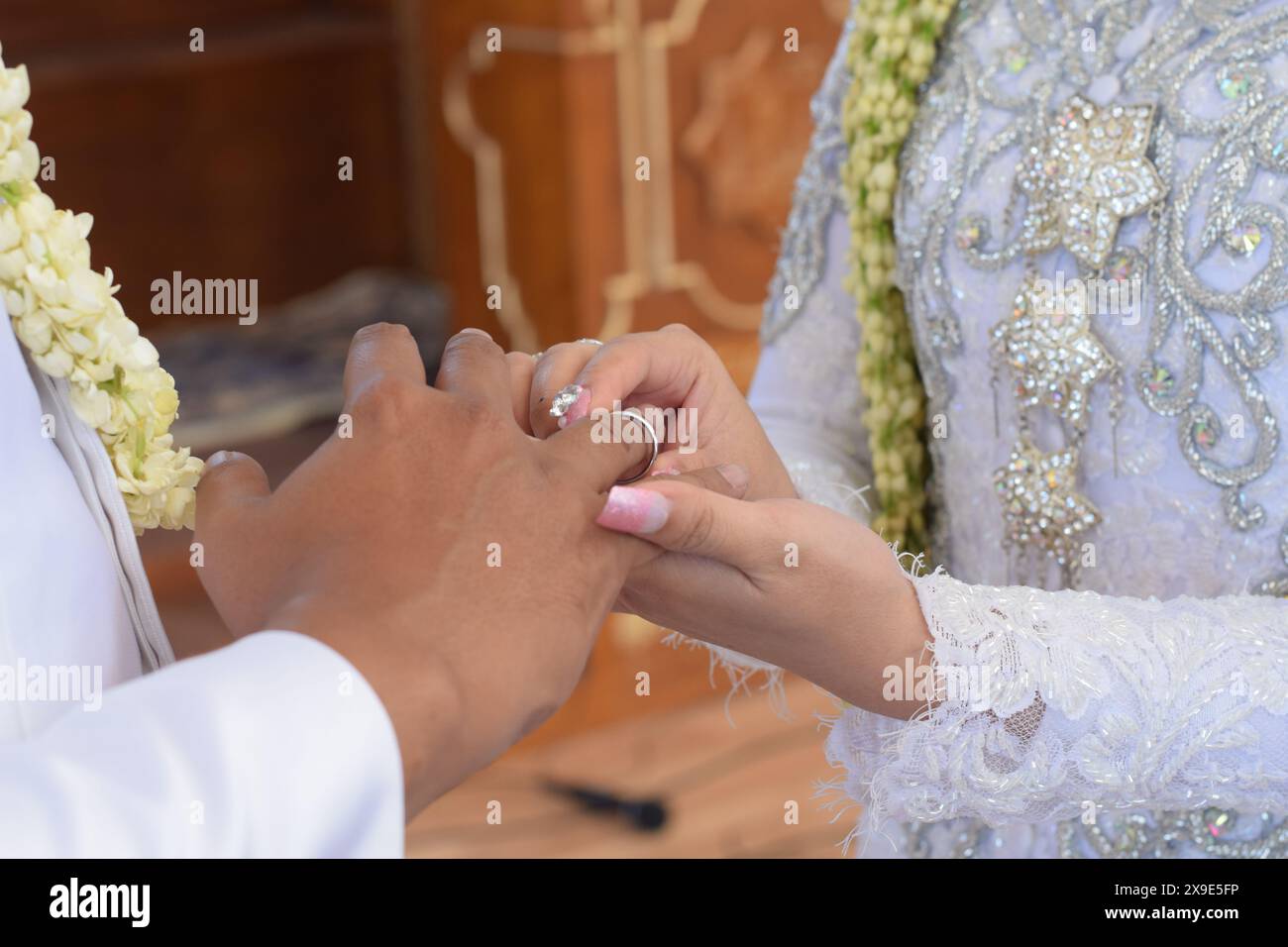 Die Braut, der Ehering und der Bräutigam halten die Hände. Zeigen die Wärme ihrer Beziehung, Liebe und Respekt zueinander. Stockfoto