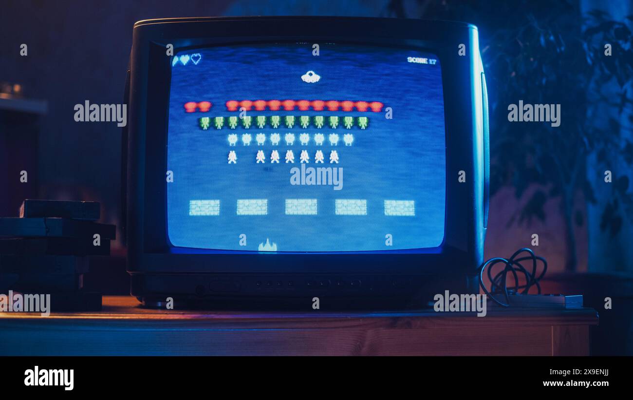 Nahaufnahme eines Retro-Fernsehbildschirms mit einem 8-Bit-Videospiel mit 2D-Design für die Konsolen-Arcade-Videospiele der 80er Jahre. Nostalgisches Shooter-Spiel, Spieler kämpfen mit Schwarm von Außerirdischen und gewinnen das härteste Level. Stockfoto