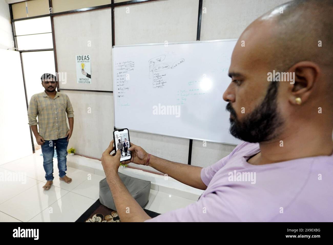 Ajmer, Indien. Mai 2024. Divyendra Singh Jadoun, Eigentümerin von Polymath Synthetic Media Solutions, demonstriert mit einem Kollegen, wie Menschen Selfies mit Politikern in ihrer vertrauten Umgebung machen können. Unter anderem erstellt das Unternehmen Deepfake-Videos für Wahlkampagnen. Quelle: Himanshu Sharma/dpa/Alamy Live News Stockfoto