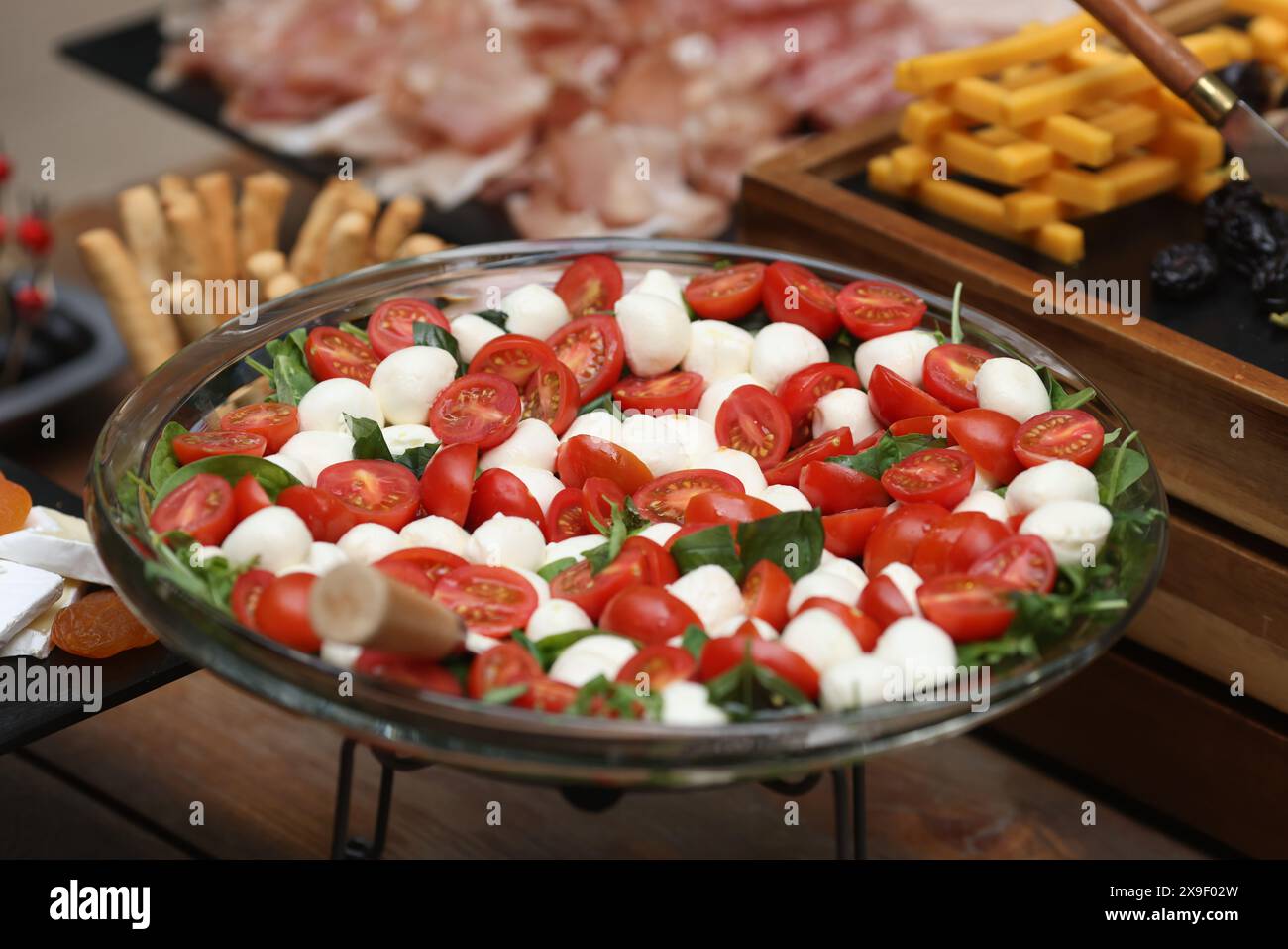 Geringe Schärfentiefe (selektiver Fokus) mit Tomaten, Mozzarella und Basilikumsalat am Buffet. Stockfoto