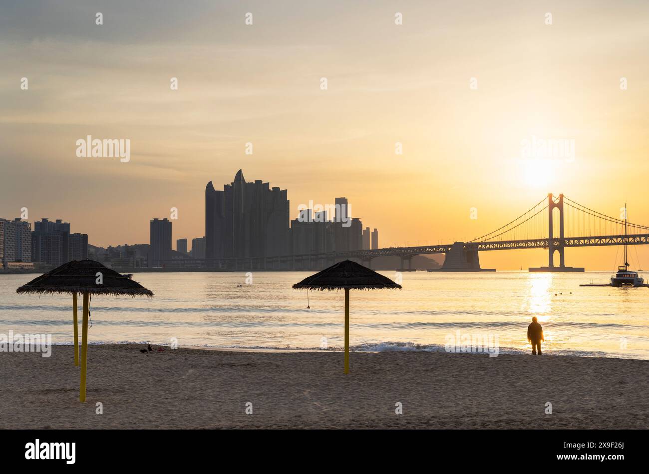 Mann am Gwangalli Beach mit Gwangan Bridge im Hintergrund bei Sonnenaufgang, Busan, Südkorea Stockfoto