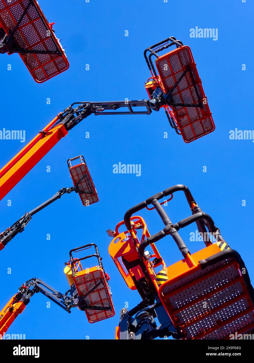 Große Gruppe von Gelenkkranen, Körben und hydraulischen Armen hoch in einem klaren blauen Himmel, Perspektive aus flachem Winkel. Stockfoto