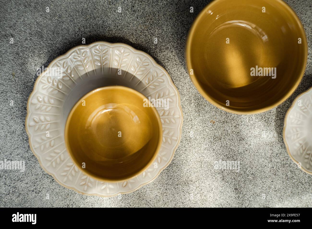 Blick von oben auf vier leere Keramikplatten und -Schüsseln auf einem Tisch Stockfoto