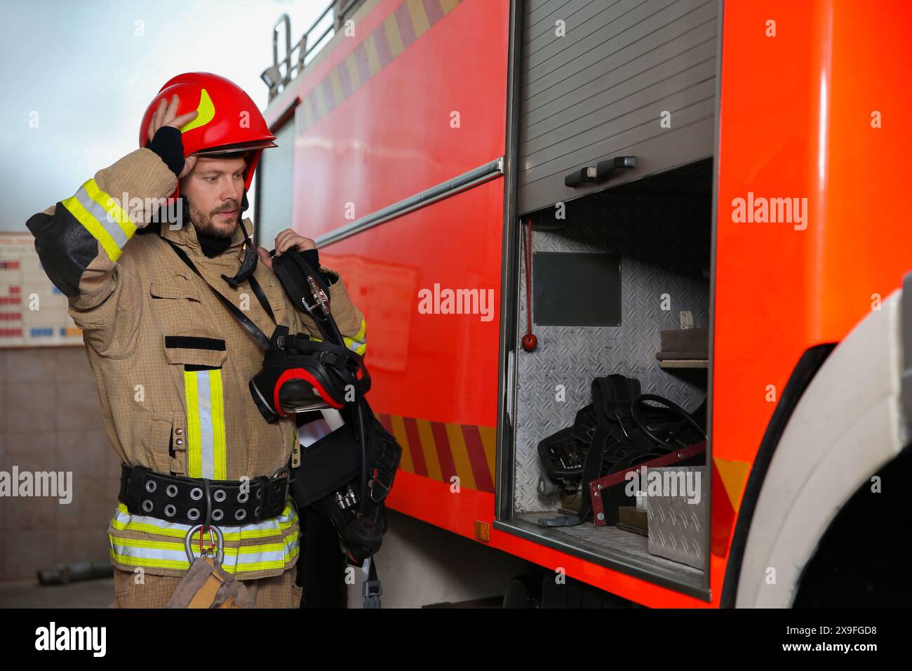 Feuerwehrmann in Uniform in der Nähe des Feuerwehrwagens auf der Station Stockfoto