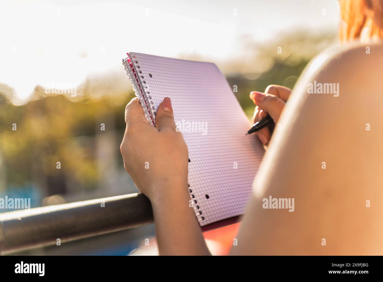 Frau schreibt in einem Notizbuch während einer Outdoor-Lernsitzung bei Sonnenuntergang - Fokus und Konzentration, gesunder Lebensstil, heller und sonniger Tag, aktiv und d Stockfoto
