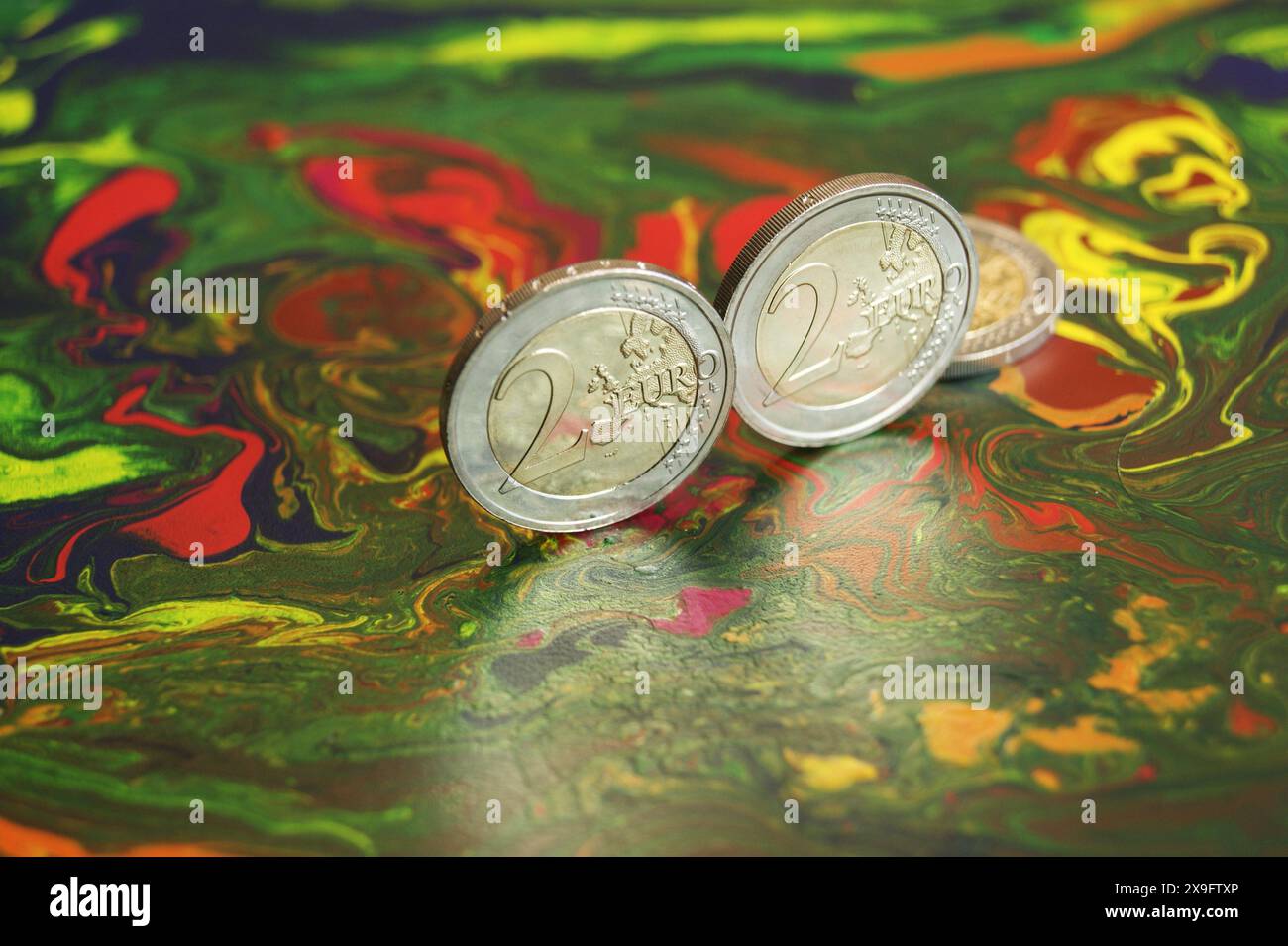 Glänzende neue 2-Euro-Münzen auf einer abstrakten melierten Oberfläche. Stockfoto