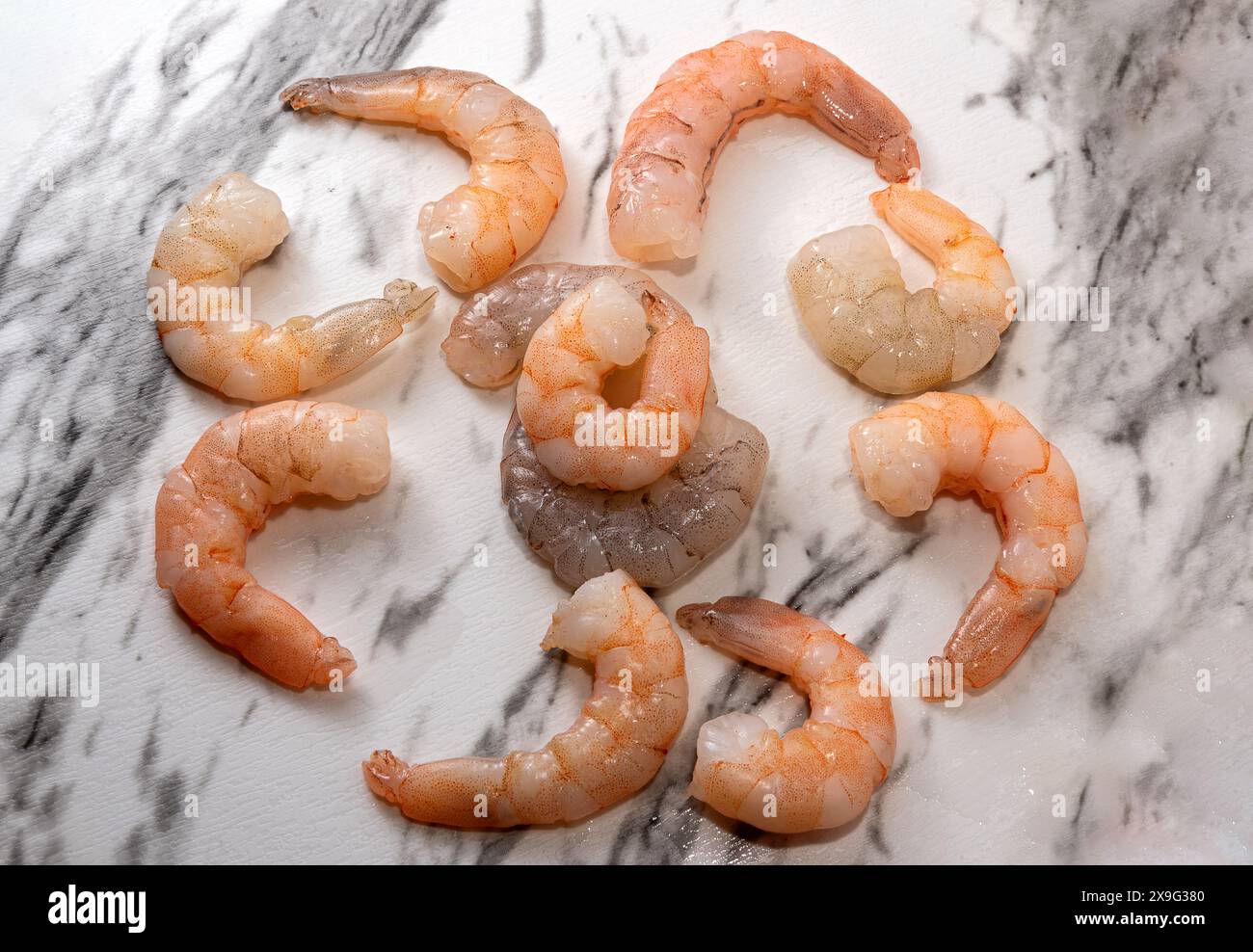 Rohe Shrimps auf weißem Marmor mit schwarzen Streifen Stockfoto