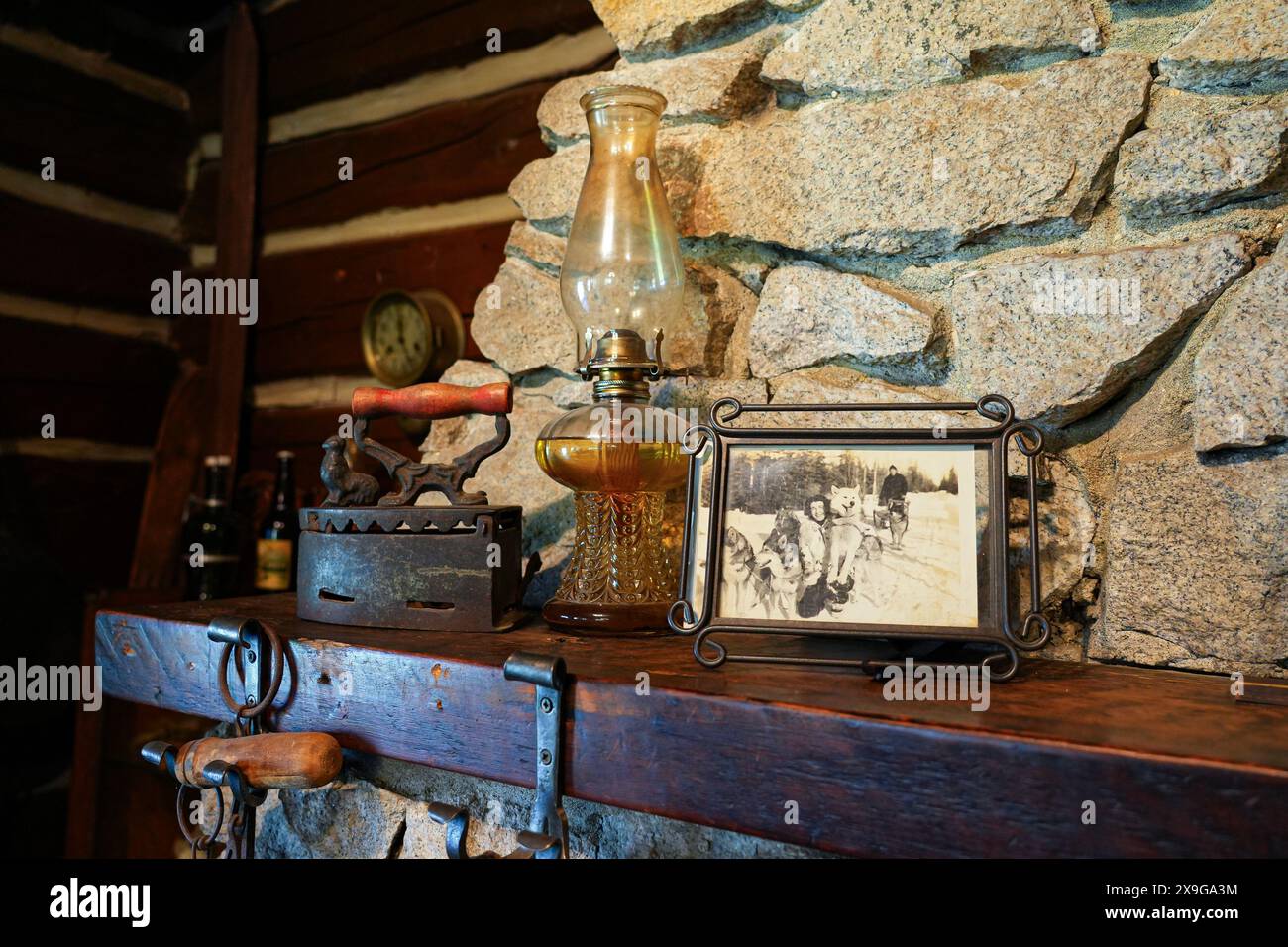 Historisches gerahmtes Foto und Bügeleisen im Blockhaus der Historic Taku Glacier Lodge, einer Holzhütte in den Bergen nördlich der Alaska Cap Stockfoto