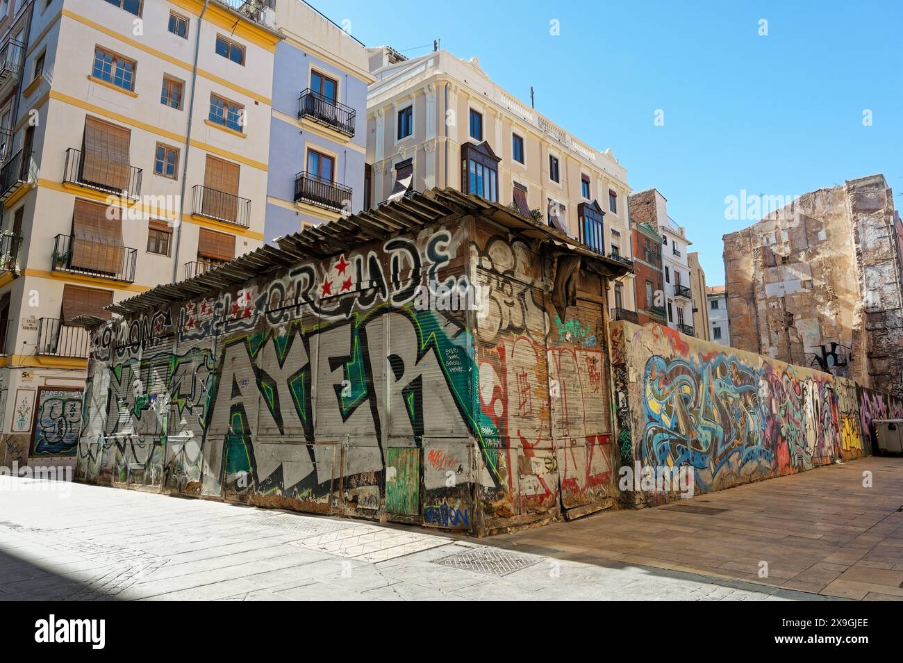 Ibrant Multi-Künstler Graffiti bedeckt ein altes Gebäude in Valencia und hebt sich vor dem Hintergrund modernerer Architektur hervor Stockfoto