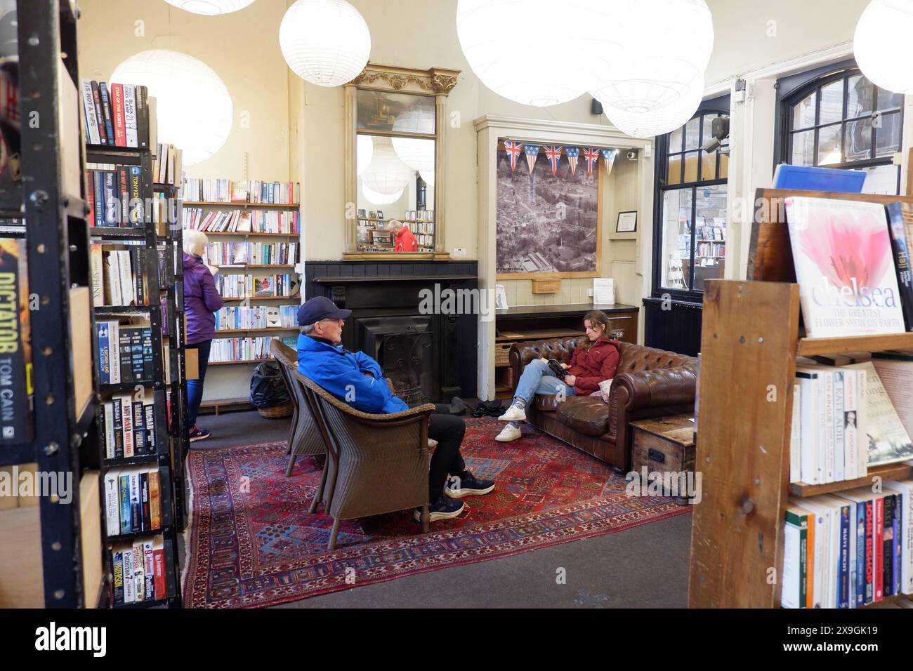 Kunden lesen am offenen Feuer bei Barter Books, einem berühmten und riesigen Second-Hand-Buchladen im ehemaligen Bahnhofsgebäude in Alnwick Northumberland Stockfoto