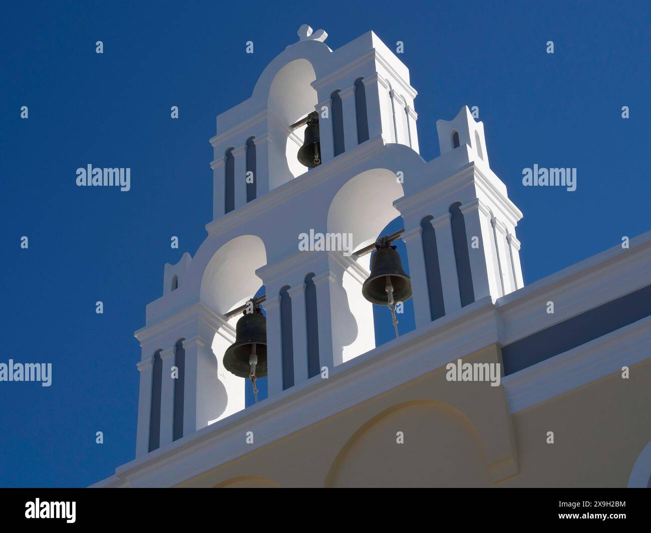 Weißer Glockenturm einer Kirche vor einem blauen Himmel in Griechenland, die Vulkaninsel Santorin mit blauen und weißen Häusern und Kirchen, Blumen und Stockfoto