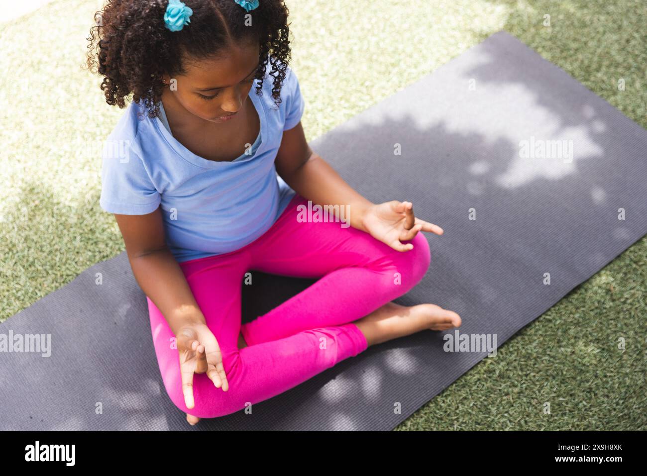 Biracial Girl praktiziert Yoga im Freien in der Schule, mit Kopierraum Stockfoto
