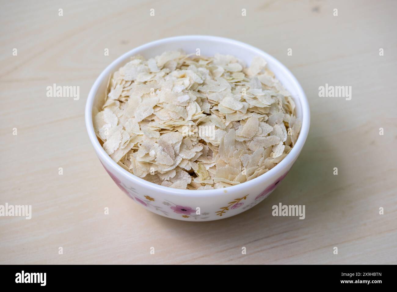 Flacher Reis oder Chira auf einer weißen Schüssel auf einer hölzernen Oberfläche. Es ist auch bekannt als pohe, aval, Pauwa, sira, Chivda, oder Avalakki. Stockfoto