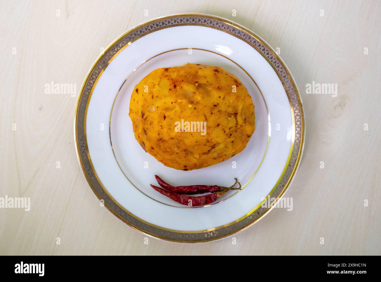 Köstliches Alu Bharta auf einem weißen Teller auf hölzernem Hintergrund. Aloo Bhorta ist das einfachste und traditionellste Essen aus Bangladesch Stockfoto