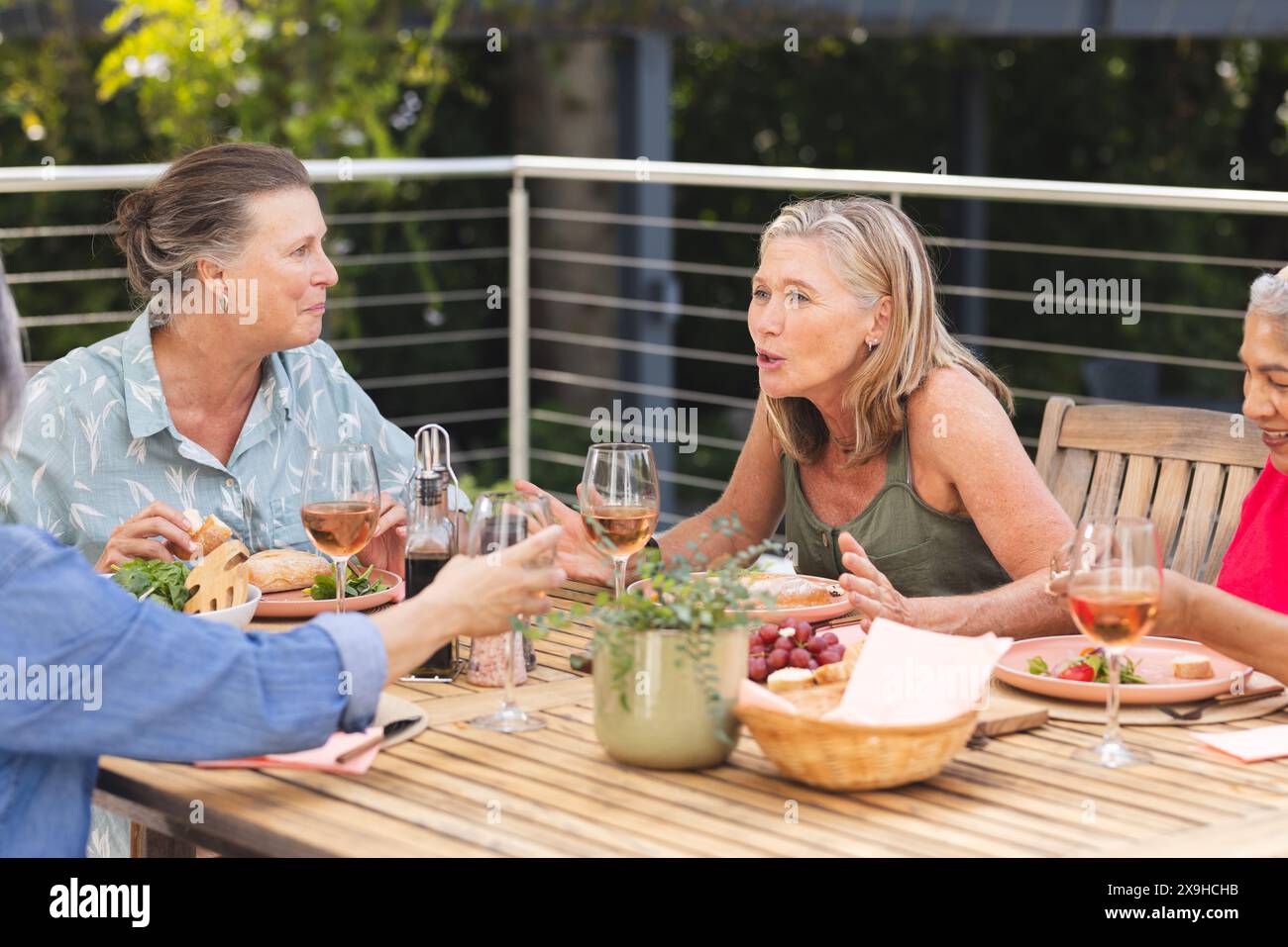 Verschiedene ältere Freundinnen genießen Essen im Freien, plaudern und lachen Stockfoto