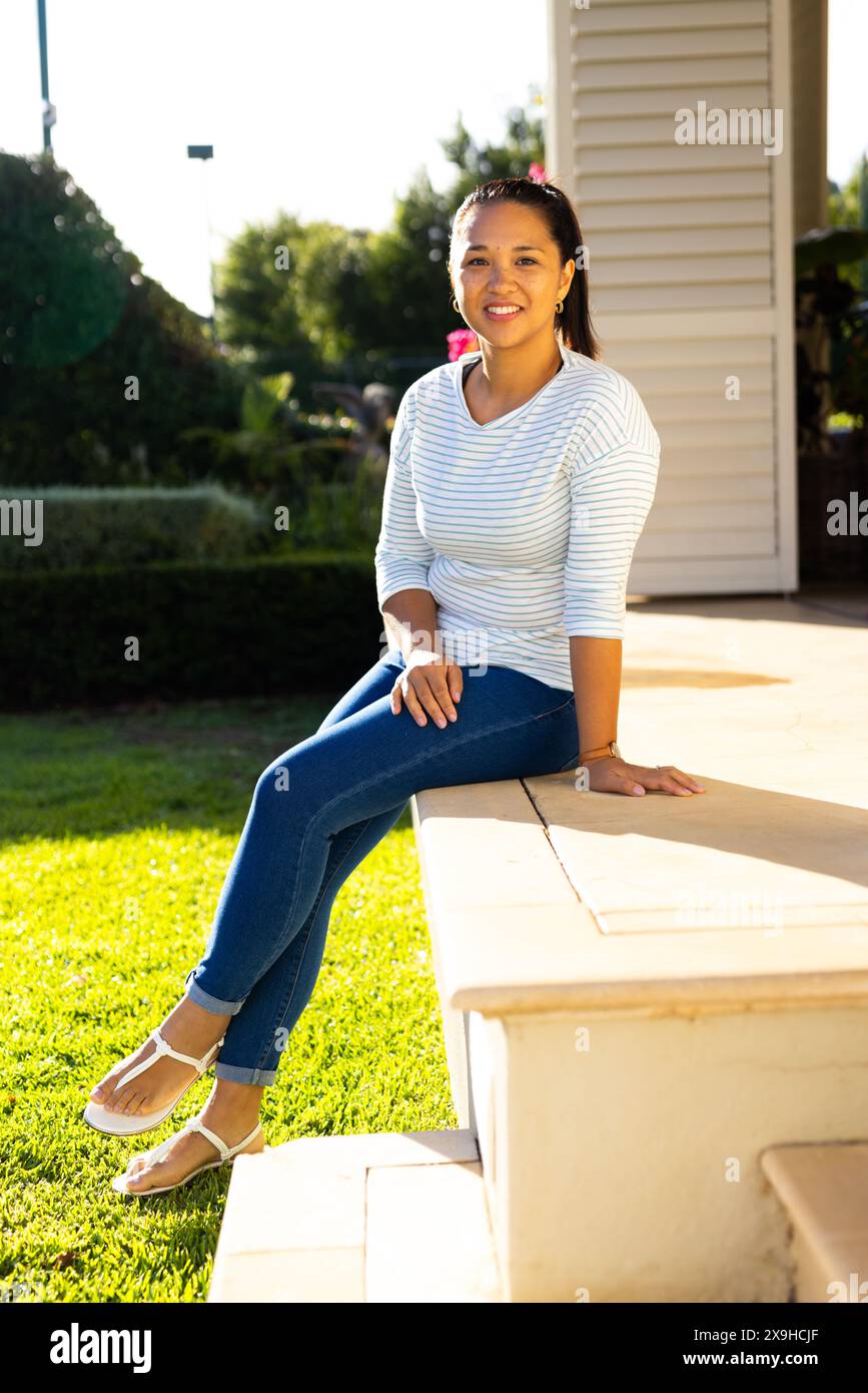 Draußen saß eine birassische Frau in ihren späten 30ern auf der Veranda und lächelte in die Kamera Stockfoto