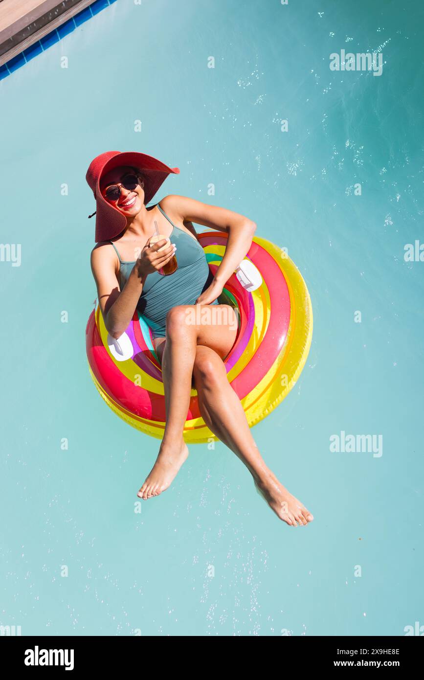 Eine birassische junge Frau, die sich draußen auf einem farbenfrohen Schwimmer entspannt Stockfoto