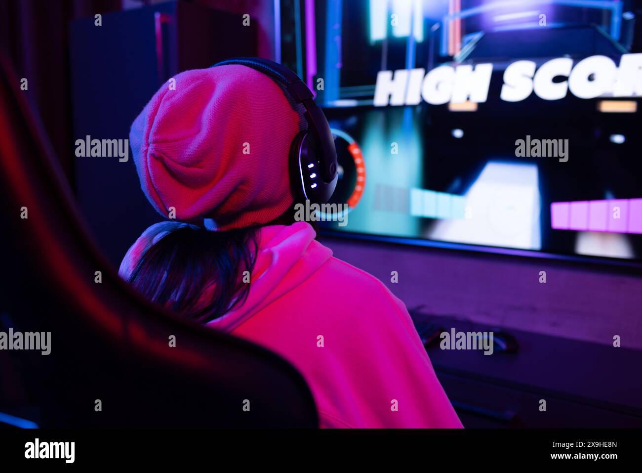 Eine zweirassige junge Frau zu Hause, die Kopfhörer trägt und Videospiele spielt Stockfoto