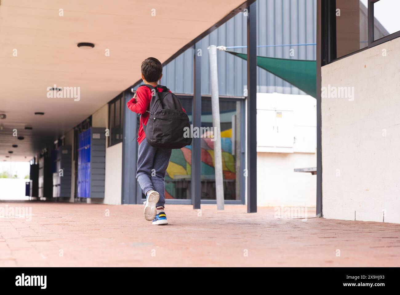 In der Schule läuft ein birassischer Junge auf dem Flur mit Kopierraum im Freien Stockfoto