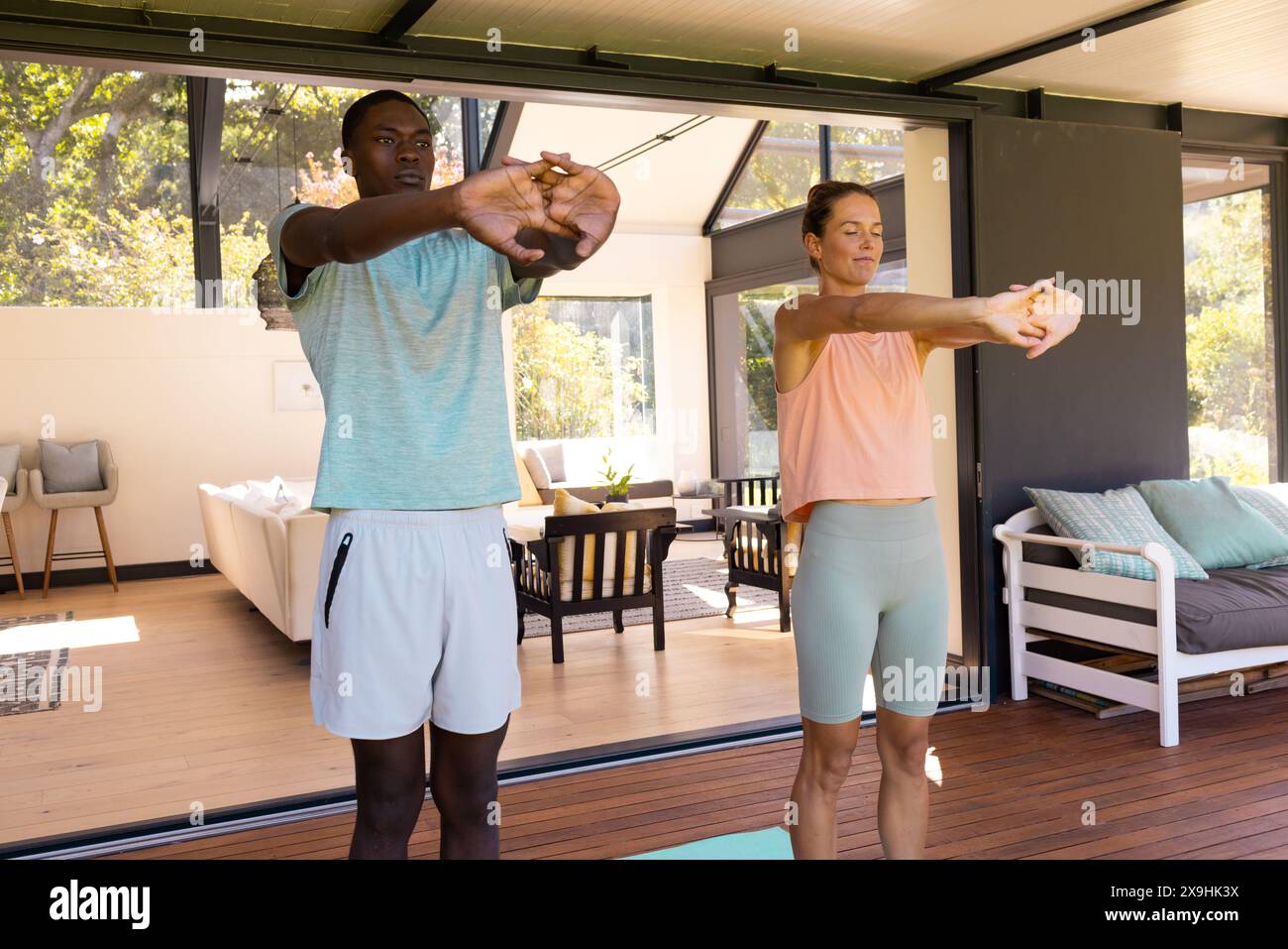 Ein vielfältiges junges Paar, das sich draußen ausdehnt, beide in sportlichen Outfits Stockfoto
