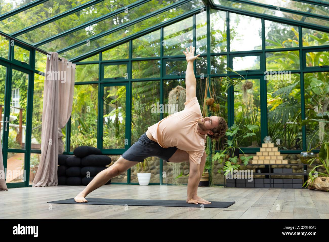 Glashaus-Studio mit kaukasischen männlichen Yogalehrern Stockfoto