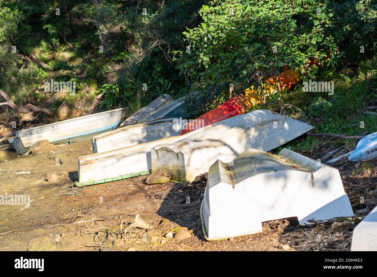 Umgekippte schmuddelige Boote/Ruderboote auf sandiger Küste Stockfoto