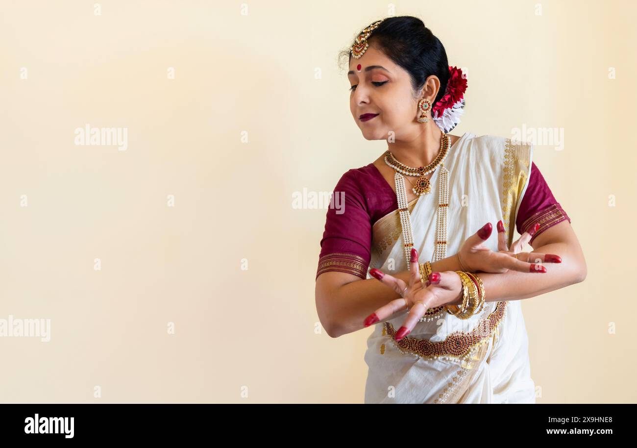 Klassische indische Tänzerin in traditionellem Tanzkostüm, die Bharatanatyam-Tanzposition (Mudra) auf hellem Hintergrund mit Kopierraum demonstriert. Stockfoto