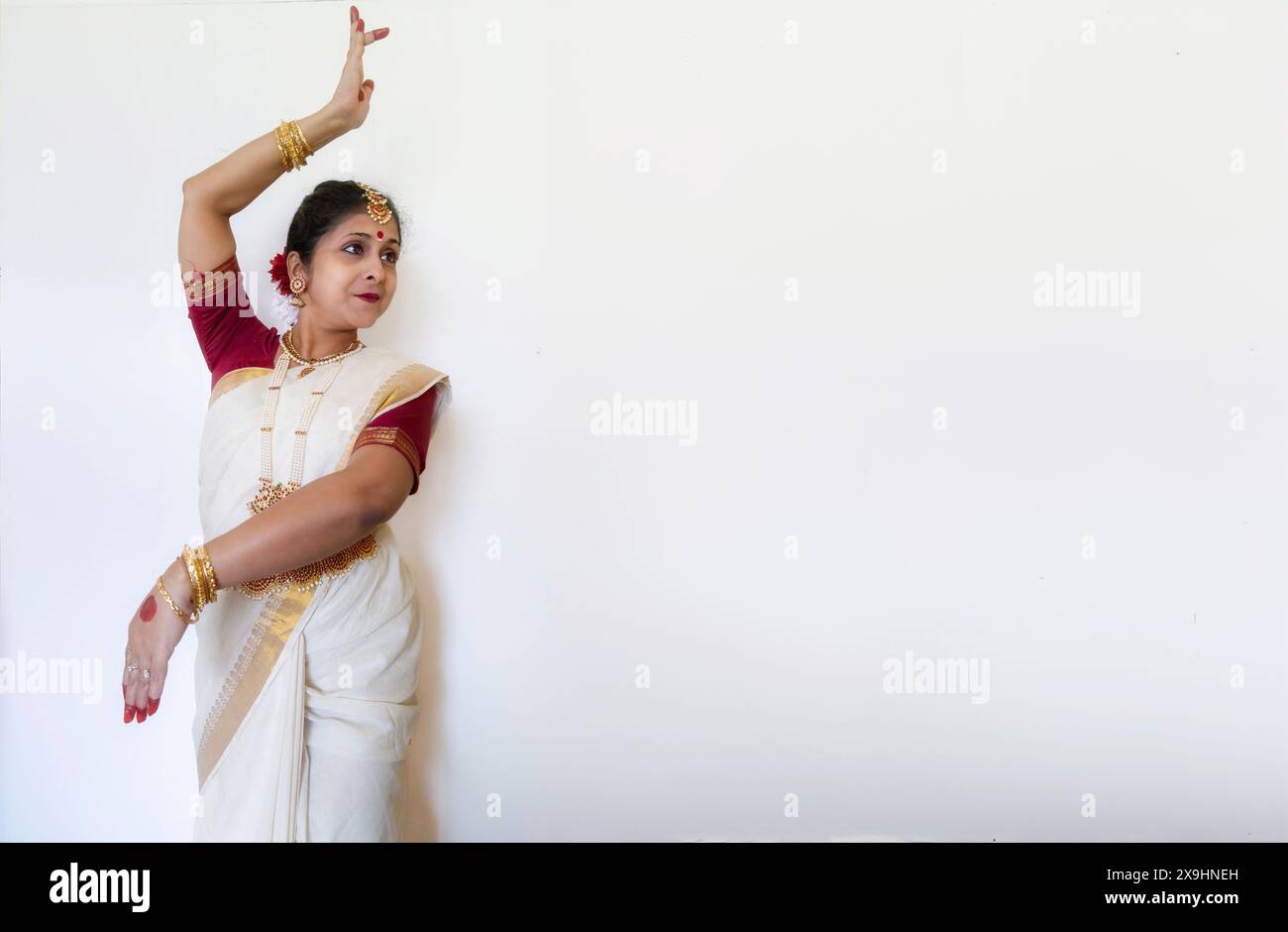 Klassische indische Tänzerin in traditionellem Tanzkostüm, die Bharatanatyam-Tanzposition (Mudra) auf hellem Hintergrund mit Kopierraum demonstriert. Stockfoto