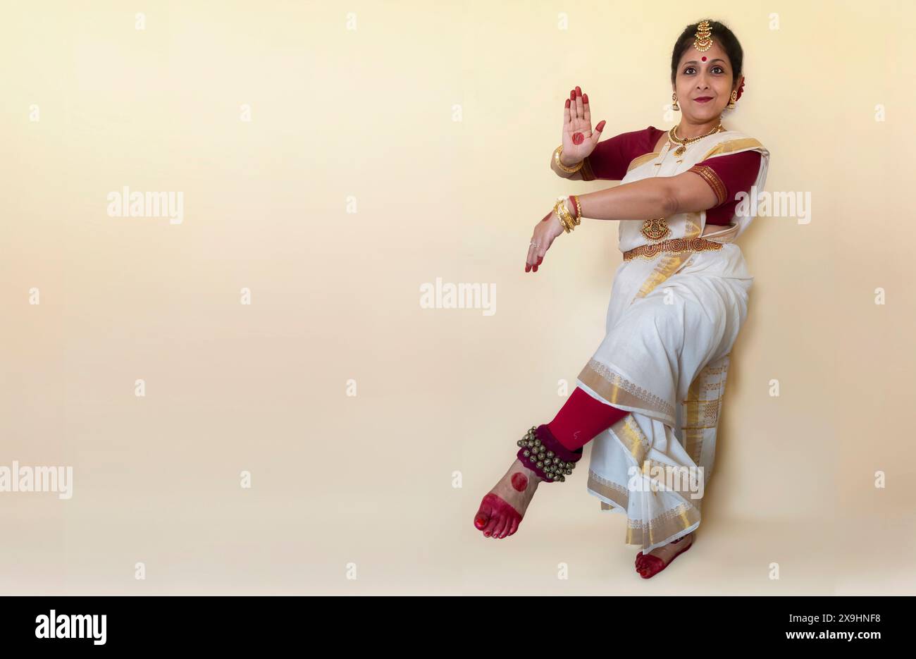 Klassische indische Tänzerin in traditionellem Tanzkostüm, die Bharatanatyam-Tanzposition (Mudra) auf hellem Hintergrund mit Kopierraum demonstriert. Stockfoto