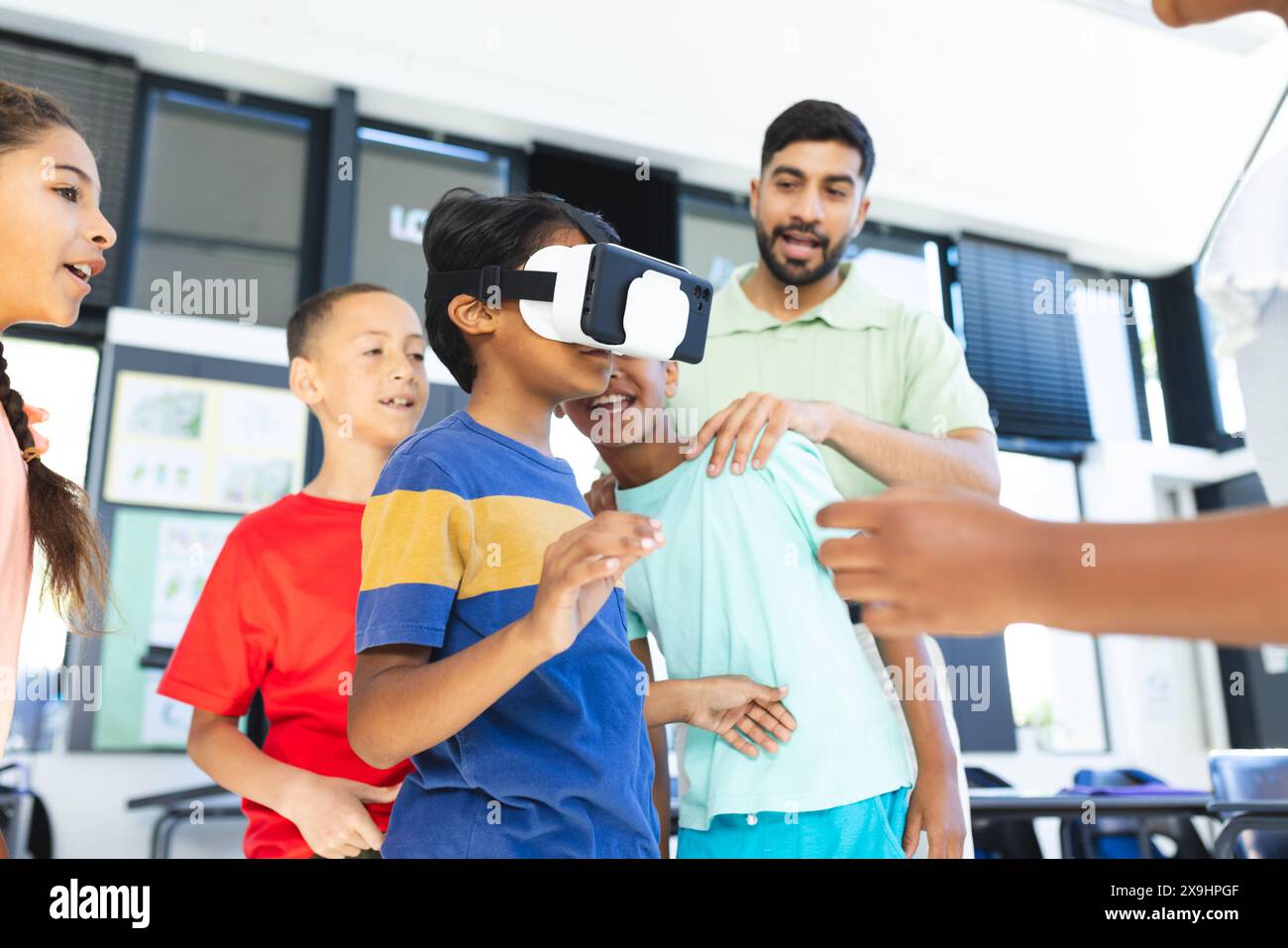 In der Schule erforschen junge Schüler und ihr asiatischer Lehrer die virtuelle Realität Stockfoto