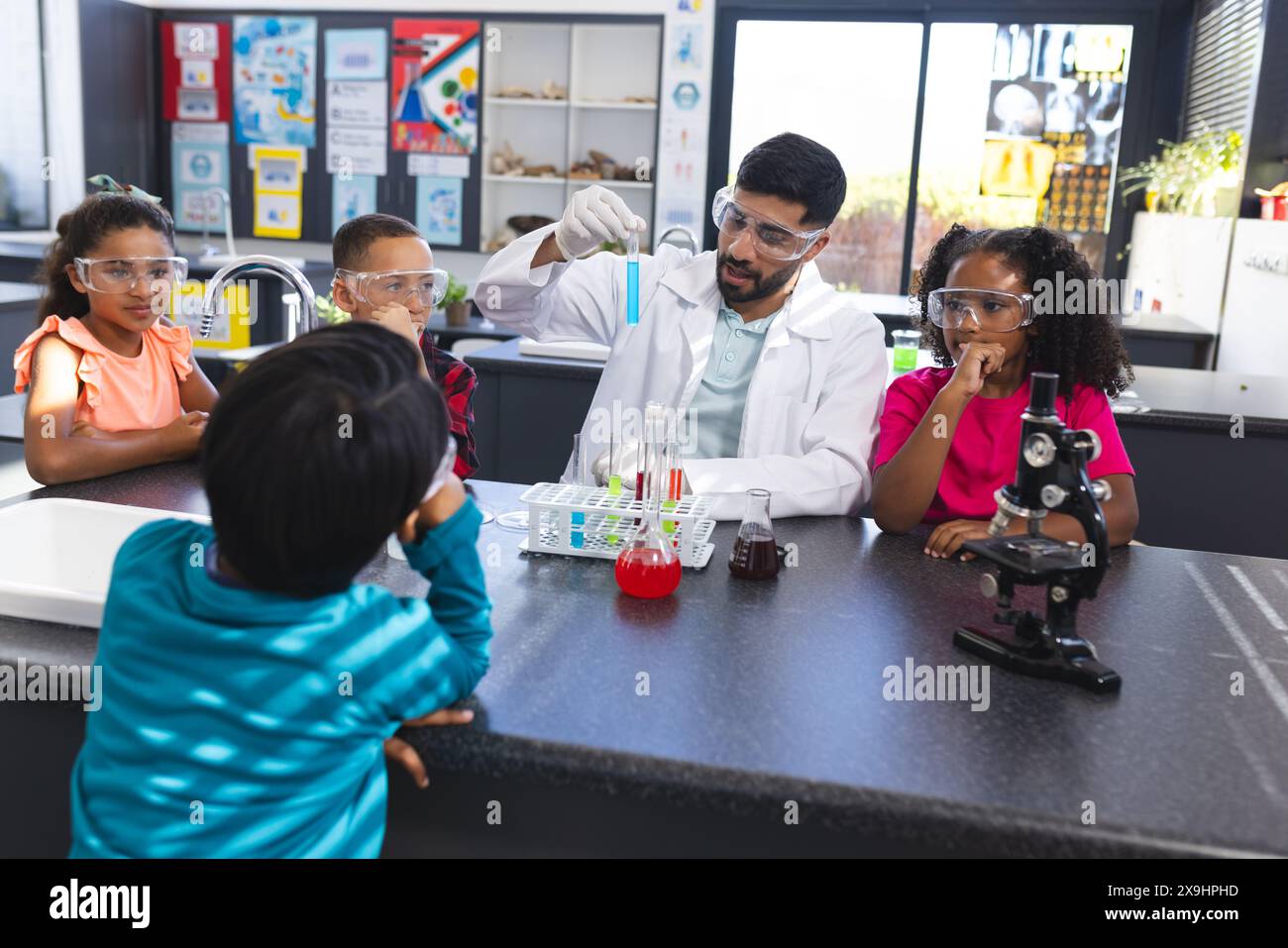 Ein junger asiatischer Lehrer führt ein Wissenschaftsexperiment für aufmerksame Kinder in der Schule durch Stockfoto