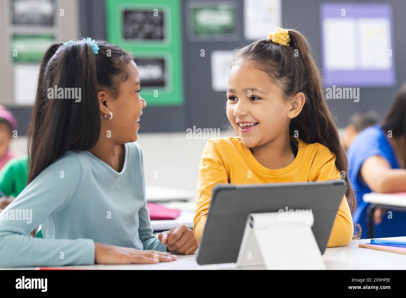 In der Schule leitete eine birassische Lehrerin ihre verschiedenen Schüler während des Unterrichts im Klassenzimmer Stockfoto