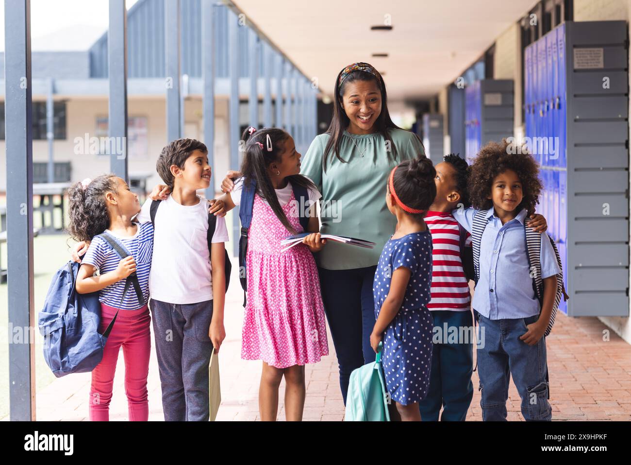 Ein afroamerikanischer Lehrer mittleren Alters mit sechs verschiedenen Kindern im Freien in der Schule Stockfoto