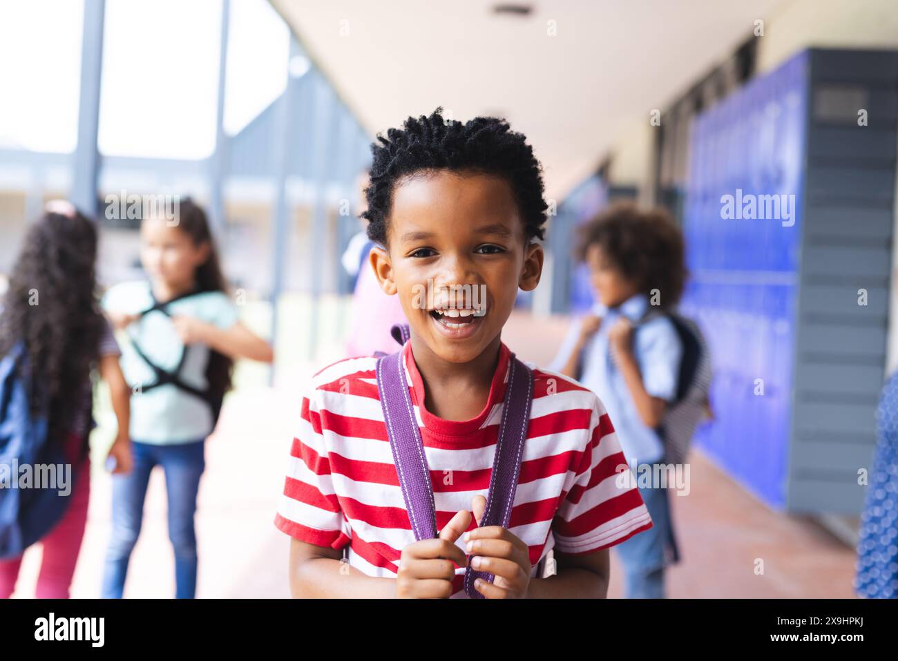 Junger afroamerikanischer Junge, der draußen in der Schule mit seinem Rucksack lächelt Stockfoto