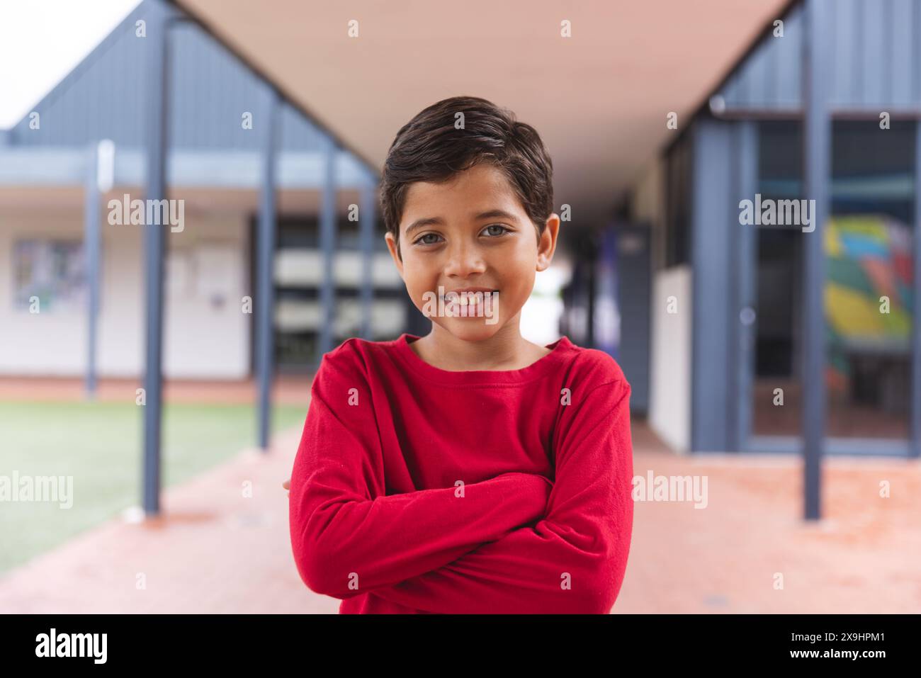 In der Schule stand ein junger männlicher Schüler mit überkreuzten Armen im Freien Stockfoto