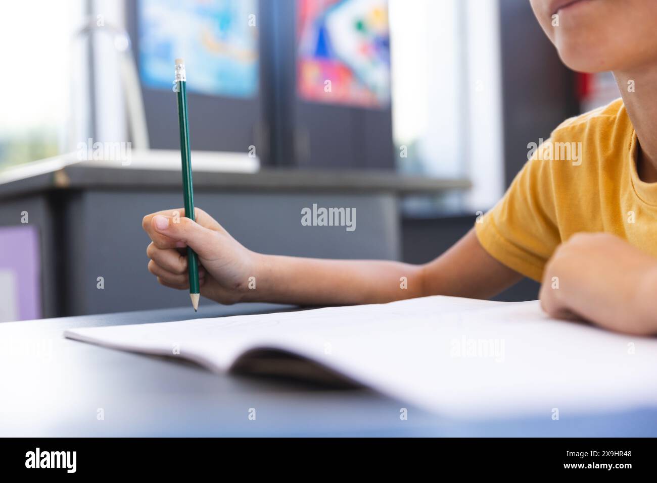 Biracial Boy konzentrierte sich auf das Schreiben in einem Klassenzimmer in der Schule Stockfoto