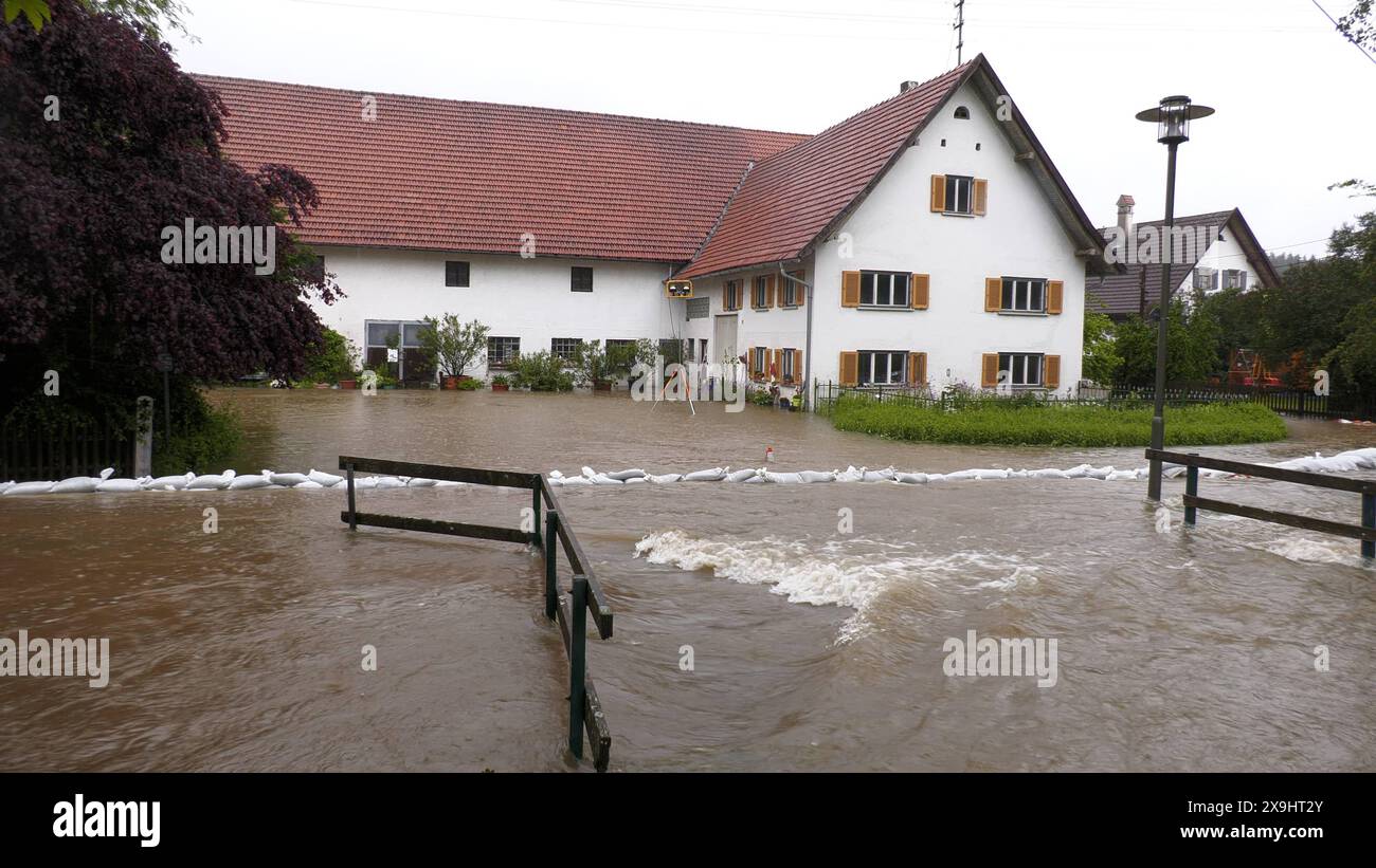 Hochwasserdrama im Unterallgäu. Extreme Regenmengen bringen die Einsatzkräfte in der Gegend um Bad Grönenbach zum Verzweifeln. Der Zellbach steigt extrem schnell an. Die errichteten Sandsackdämme reichen nicht. Das Wasser schießt über die Dämme hinweg und überflutet seit wenigen Stunden die Ortschaft Zell bei Bad Grönenbach. Die Menschen versuchen mit allem Möglichen Barrieren zu errichten. Betroffen ist in der Ortschaft auch der Friedhof. Das Wasser schießt durch das Gelände. Die Feuerwehr ist mit großen Pumpen im Einsatz. Ein Radlader versucht die Wassermassen wegzudrängen. Anwohner und Feue Stockfoto