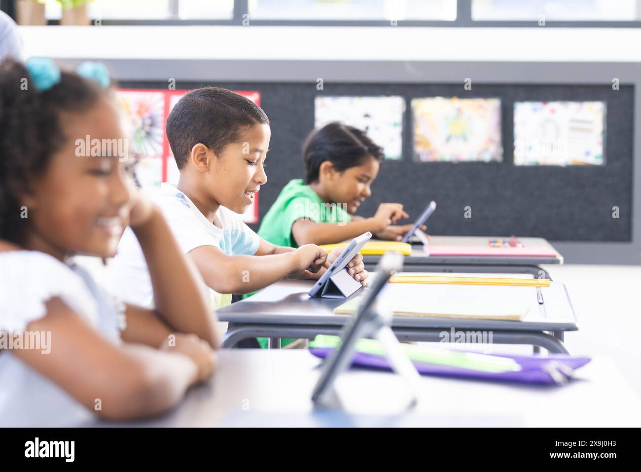 In der Schule verwenden verschiedene Schüler Tablets und Lehrerüberwachung im Klassenzimmer Stockfoto In der Schule verwenden verschiedene Schüler Tablets und Lehrerüberwachung im Klassenzimmer Stockfoto