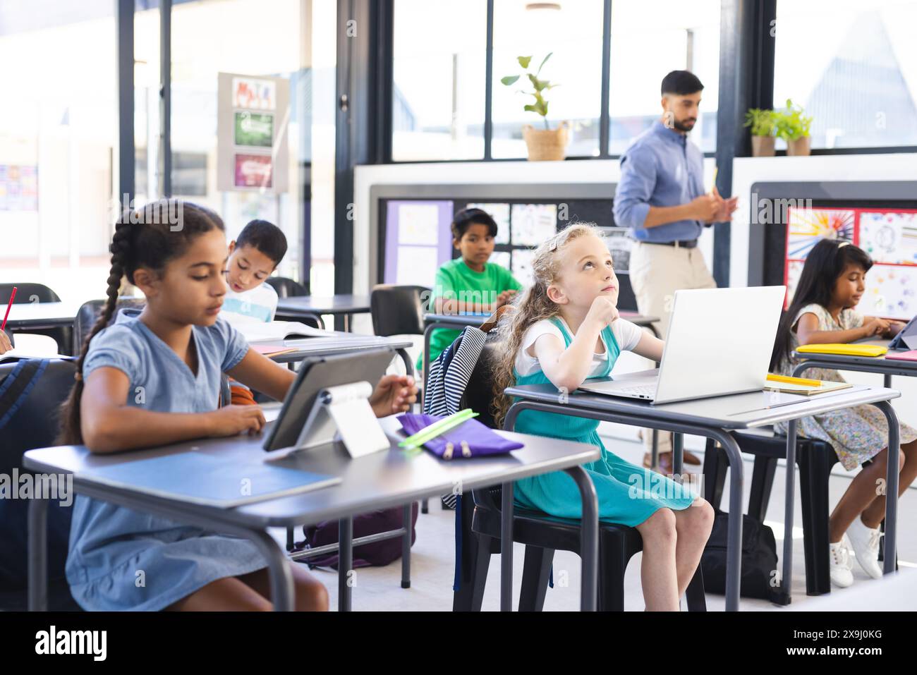 Verschiedene Kinder studieren in einem hellen Klassenzimmer, das Bildung umfasst Stockfoto