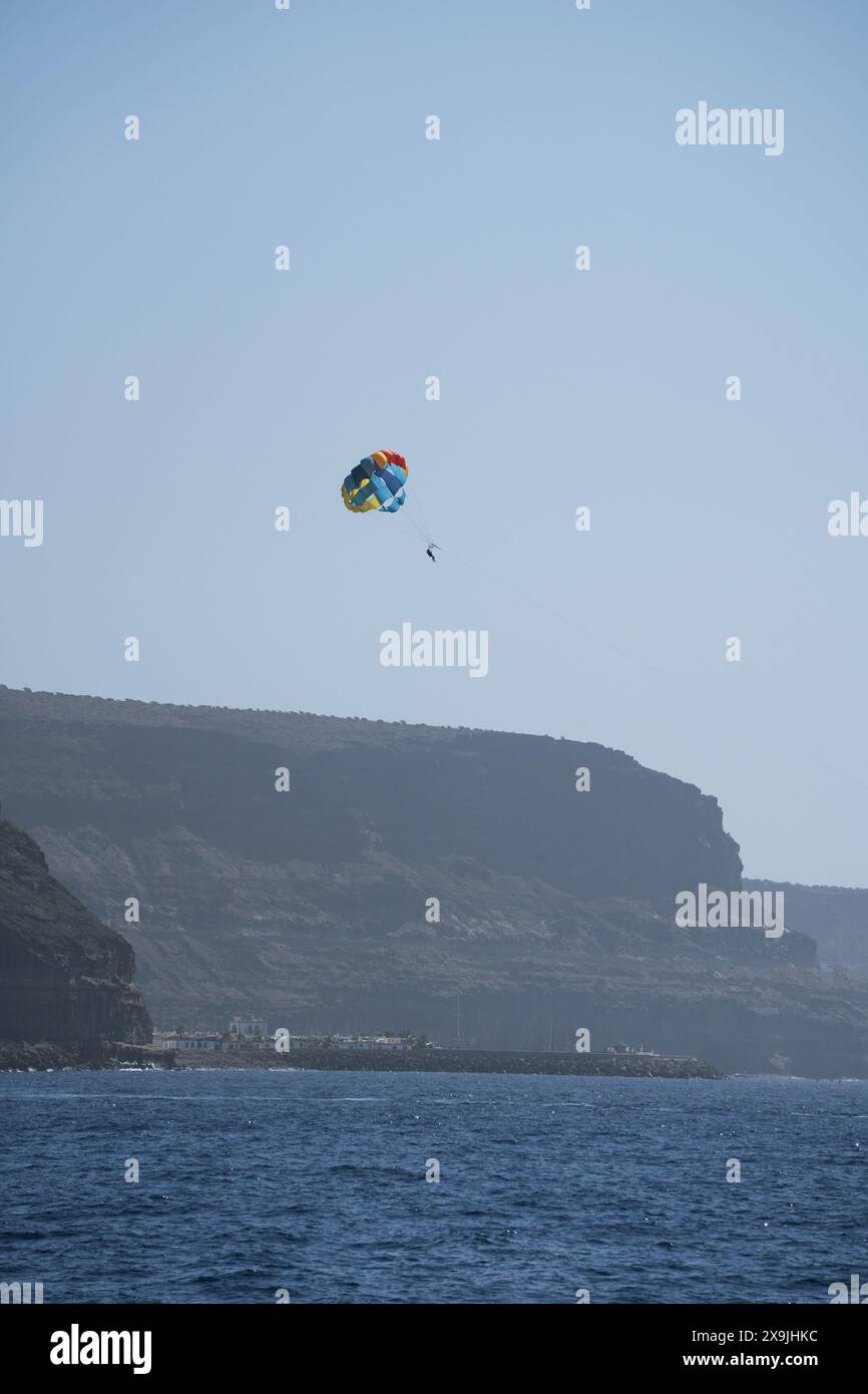 Parasailing gegen Klippen am Strand von Tauro (Spanisch: Playa de Tauro) in der Nähe des Ferienortes Puerto Rico de Gran Canaria auf Gran Canaria, Spanien Stockfoto