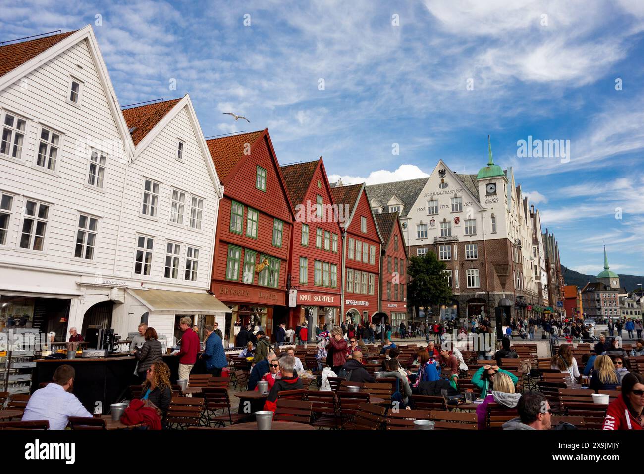 BERGEN, NORWEGEN - 11. AUGUST 2016: Touristen gehen und sitzen vor den berühmten Holzhäusern in Bergen, Norwegen Stockfoto