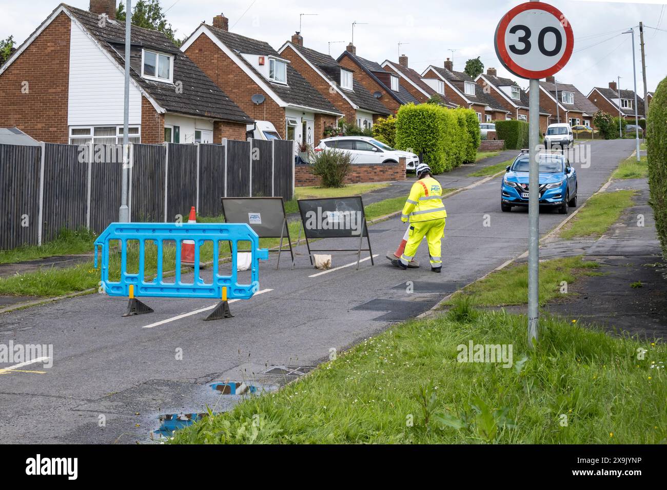 Straßeninstandhaltungsbeamter baut Barrieren auf, um die Straße zu sperren, Cherry Willingham, Lincoln, Lincolnshire, England, UK Stockfoto