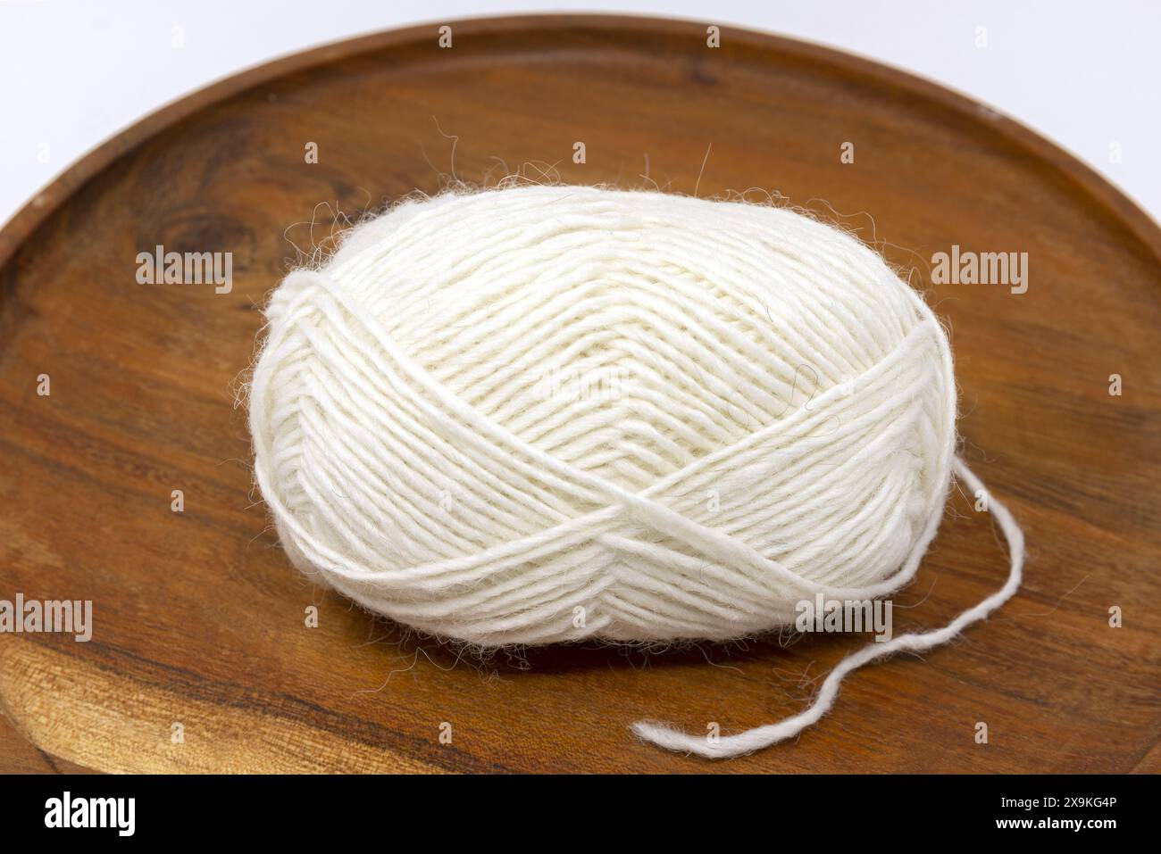 Nahaufnahme eines weißen Garnknäuels, isländischer Wollknäuel auf hölzernem Hintergrund Stockfoto