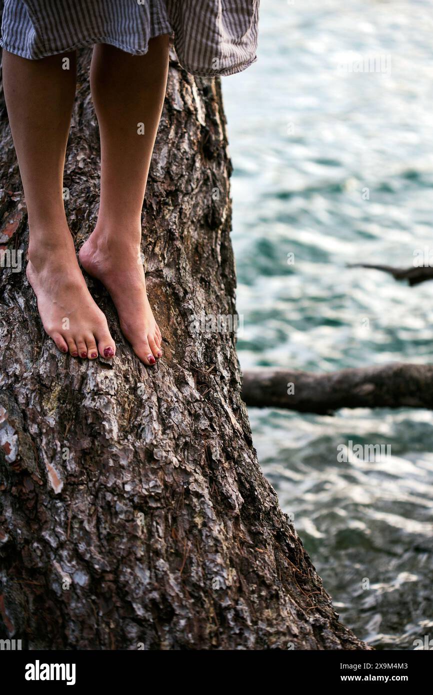 Frau, die auf einem Baum über Wasser steht Stockfoto