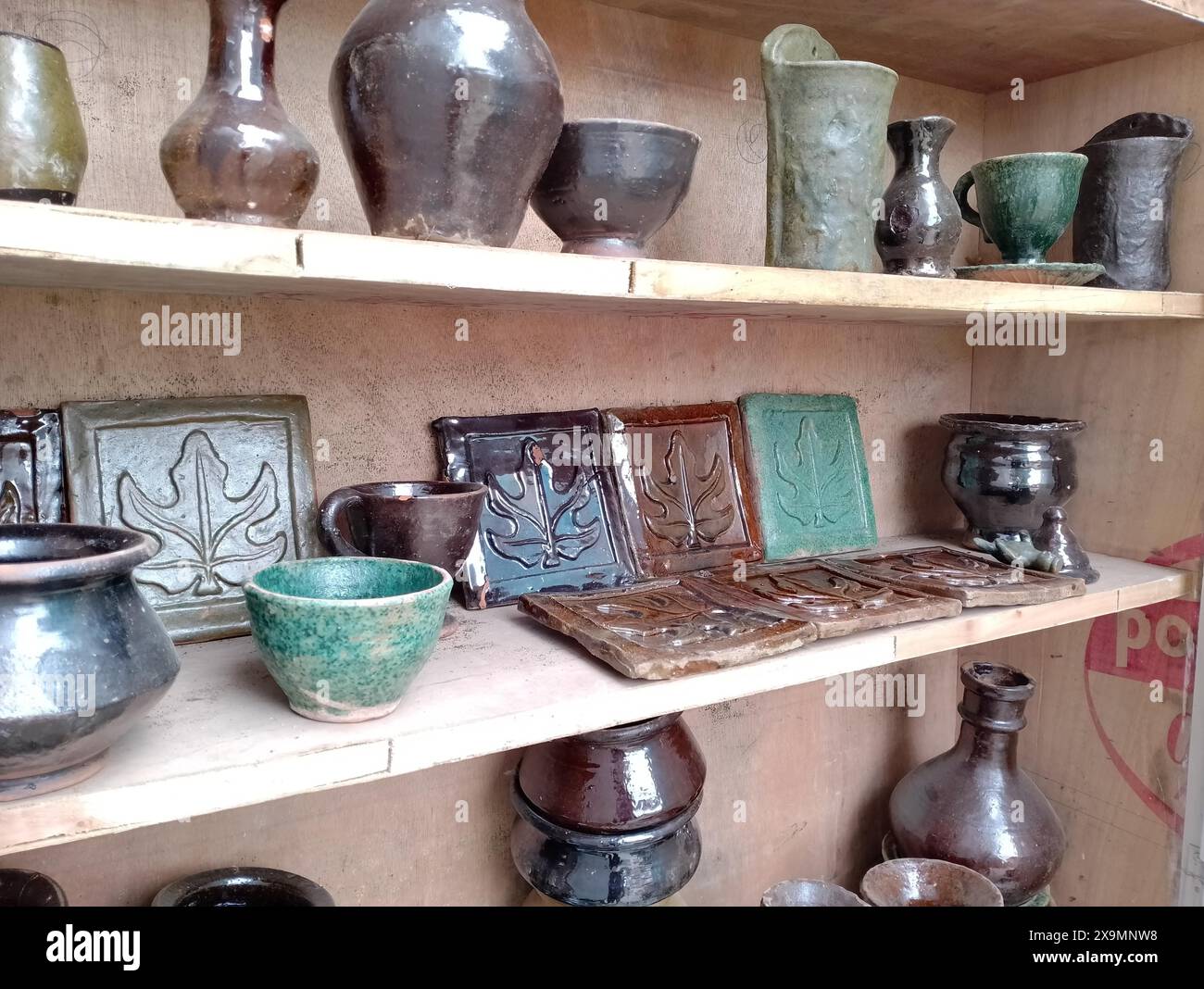Glasierte Töpferwaren auf Holzregalen mit handgefertigten Keramikkeramiken Stockfoto
