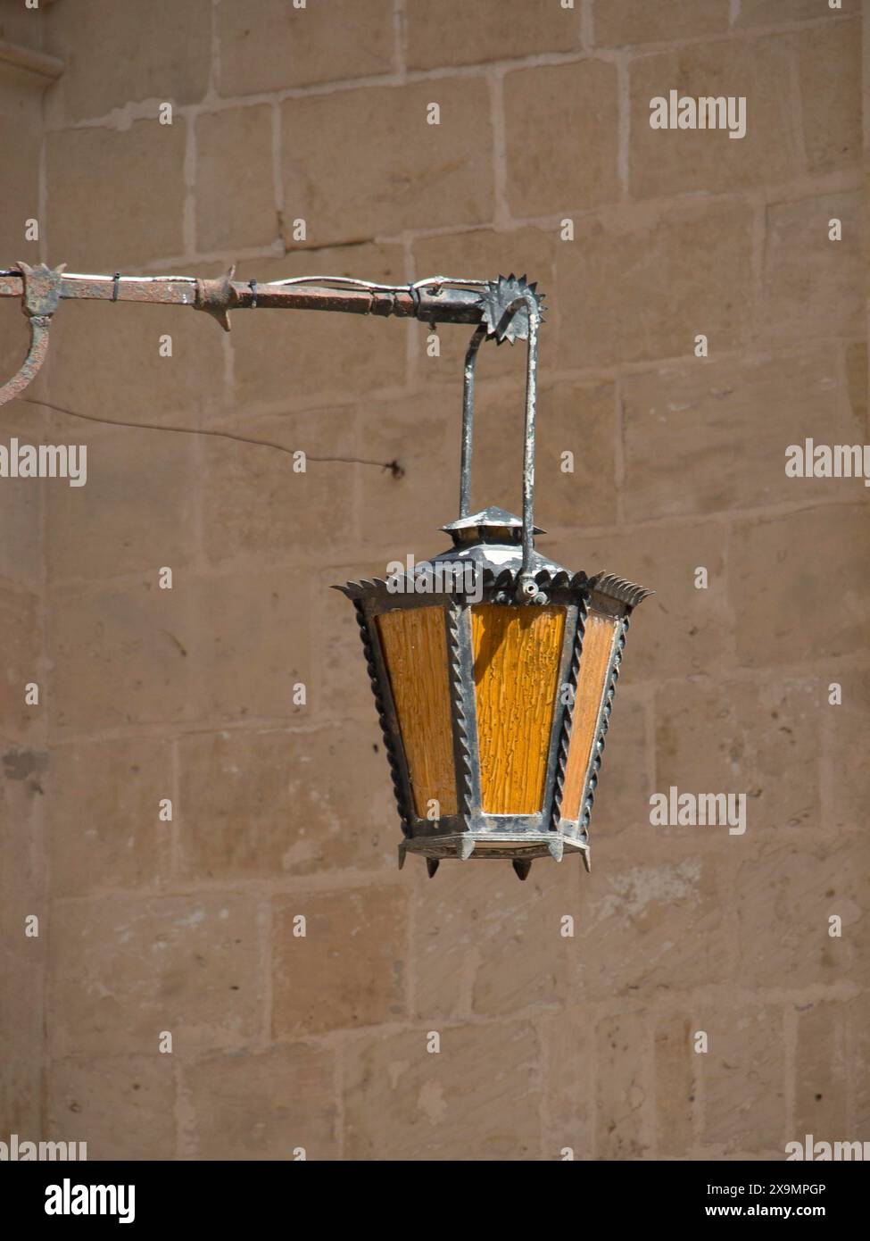 Antike Laterne aus Metall und Glas, die an einer stabilen Steinmauer aufgehängt ist, verleiht ein rustikales Ambiente, die Stadt mdina auf der Insel malta mit historischem Charakter Stockfoto