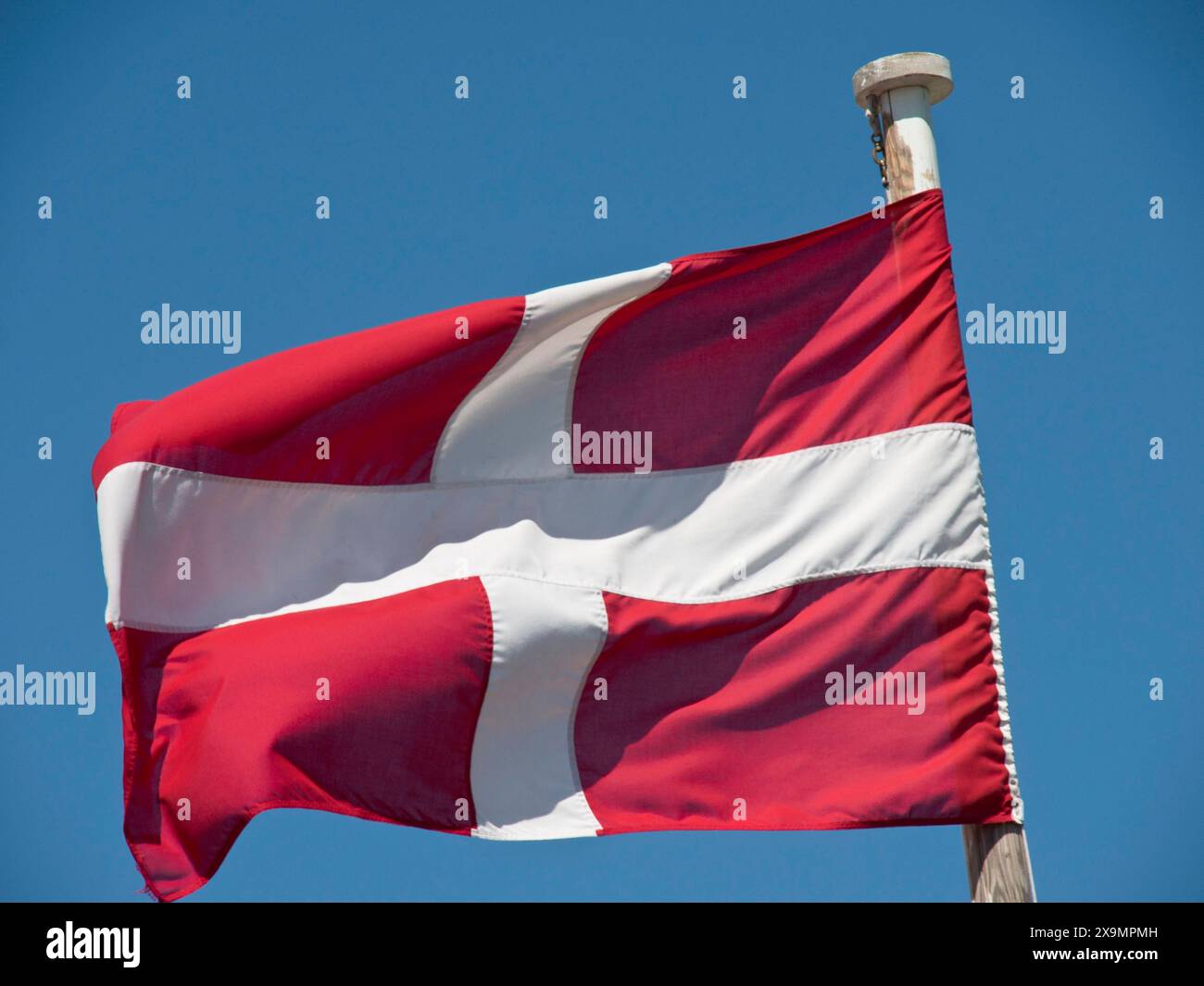 Dänische Flagge fliegt auf einem Fahnenmast vor einem klaren Himmel, die Stadt mdina auf der Insel malta mit historischen Häusern, bunten Balkonen, prächtig Stockfoto