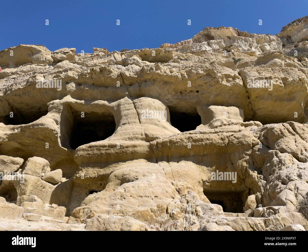 Sehen Sie nach oben zu Sandsteinfelsen am Rand der Matala Bay mit Eingängen zu Höhlen der ehemaligen römischen Nekropole, später lebenden Höhlen für Hippies Stockfoto